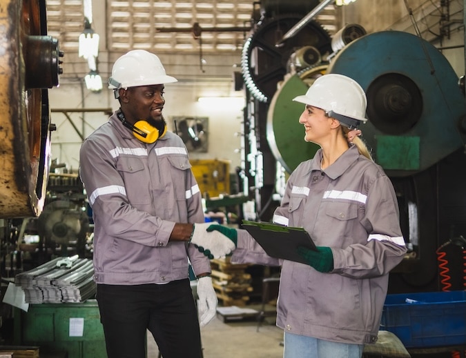 Industrial engineer technician worker man woman with helmet uniform safety vest look shake hands congratulate and agree gather work checklist inspection quality control production inside manufactory